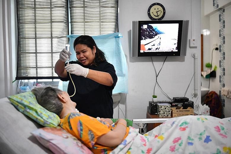 Foreign domestic worker Padua Mae Zate, 37, attending to Ms Mary Teo, 74, who is diabetic, has Parkinson's disease and is bedridden. ST PHOTO: LIM YAOHUI