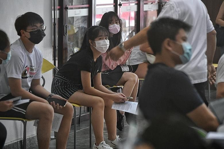 Trading strategist Samuel Wong, 51, with his daughter, Chloe, 18, who got her first dose at Tanjong Pagar CC yesterday. He says they wanted peace of mind as she is taking her A levels this year. Students waiting for their turn at the vaccination cent