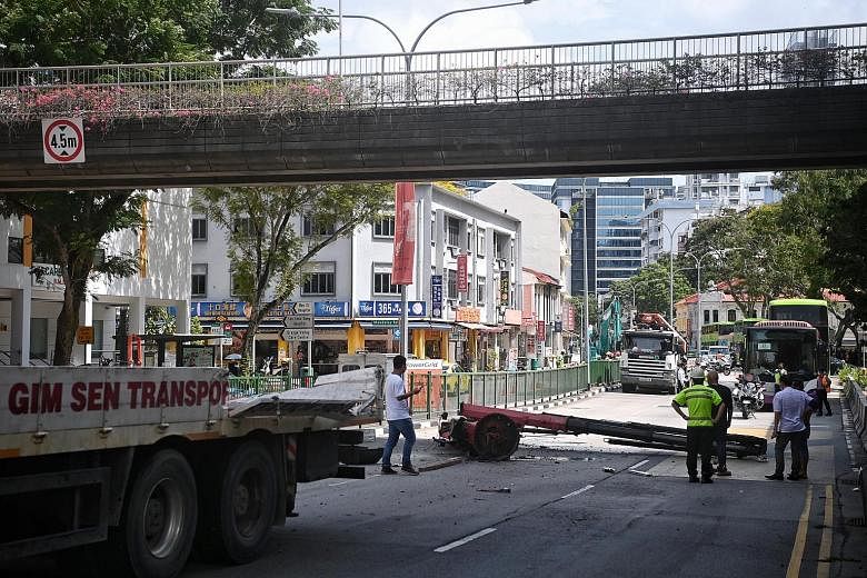 A crane arm fell from the back of a truck (left) after it hit an overhead pedestrian bridge, damaging part of it (above) and causing a major traffic jam in Balestier Road yesterday.