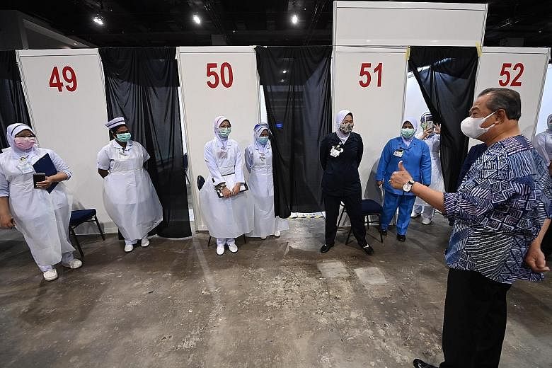 Prime Minister Muhyiddin Yassin speaking to front-line health workers at a vaccination centre at the Malaysia International Trade and Exhibition Centre in Kuala Lumpur on Friday. He says 300 more vaccine centres will open "as soon as possible" to add