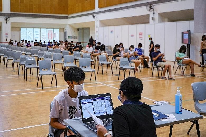 Students at a vaccination centre at ITE College Central on Monday. The Ministry of Health said those in the eligible age group of 12 to 39 can register online from today. Children who turn 12 this year must have crossed their birthday before they are