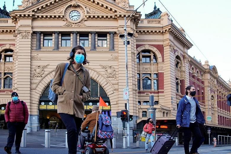 Pedestrians outside Flinders Street station in Melbourne last Friday, the first day of eased Covid-19 restrictions for the state of Victoria following an extended lockdown. With the state reporting just one new local infection yesterday for the secon