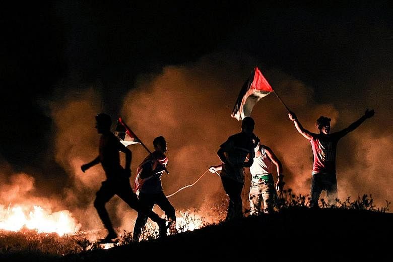 Palestinians with national flags amid burning tyres during a demonstration east of Gaza City by the border with Israel on Tuesday, as they protested against the far-right Jewish flags march in Jerusalem's Old City.