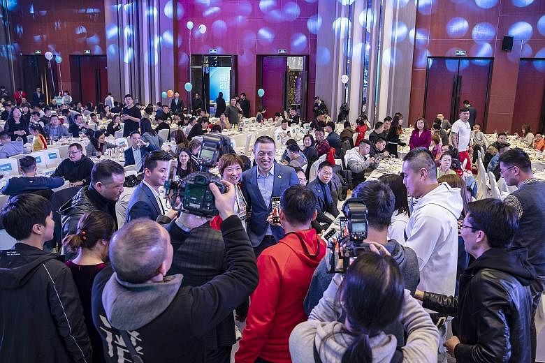 Nio founder William Li (centre) posing for photographs with car owners during a gala dinner in Shanghai in March. While other billionaire executives may cringe at spending their downtime glad-handing customers, Mr Li relies on creating a sense of all