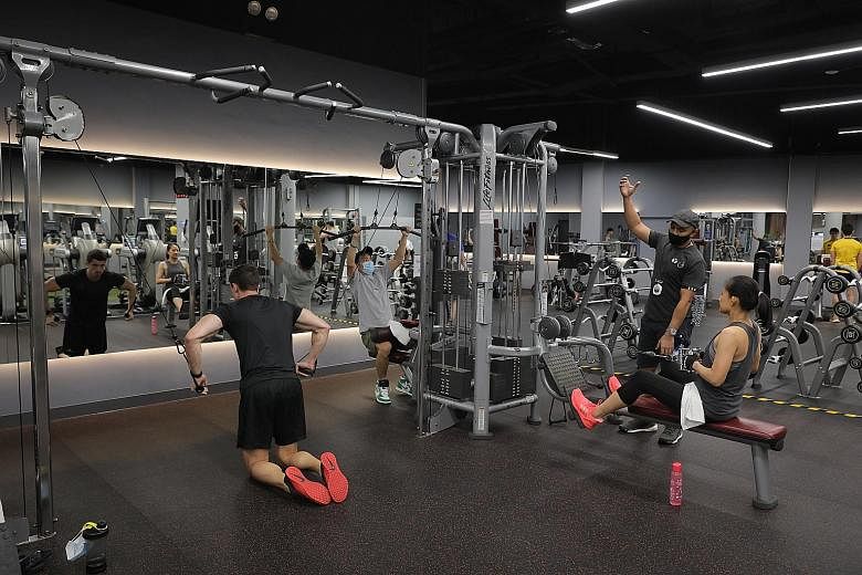 Fitness enthusiasts working out at TFX Millenia Walk yesterday for the first time since stricter Covid-19 measures led to the suspension of indoor, mask-off activities on May 8. Almost 300 members had checked into the 41,700 sq ft branch by 1pm yeste