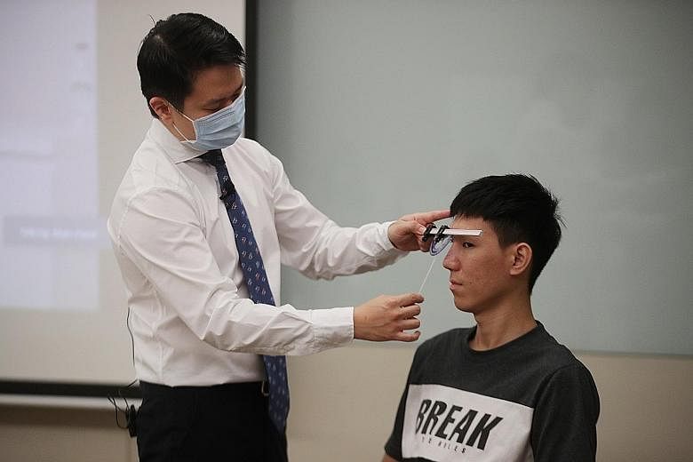Dr Ng Chew Lip (far left), an ear, nose and throat surgeon trained in facial plastic surgery, using a rhinoscale on patient Loo Jia Heng, who had traumatic nasal fractures and underwent preservation rhinoplasty surgery last month.
