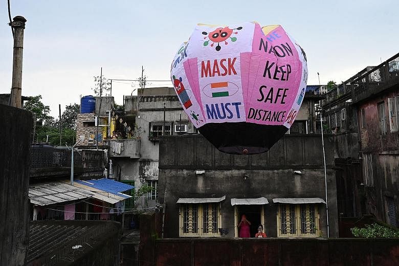 Residents in Kolkata taking photos of a paper lantern with Covid-19 guidelines and reminders on it on Tuesday. India yesterday reported 50,848 new Covid-19 cases in the past 24 hours, taking its total number of cases to more than 30 million. People s