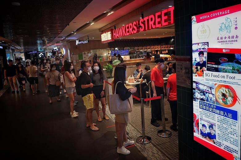 People waiting in line at Hawkers' Street in Ion Orchard mall yesterday on the first weekend since dining in was allowed to resume in groups of two. Many families took the opportunity to eat out as this is the last weekend of the school holidays. ST 