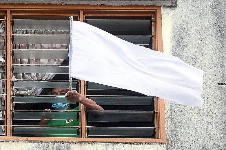 A man waving a white flag at his flat in Puchong, Malaysia. The movement called #benderaputih (white flag) on social media was started by Malaysians for those in need of food and other essentials. It signals the growing desperation of Malaysians, as 