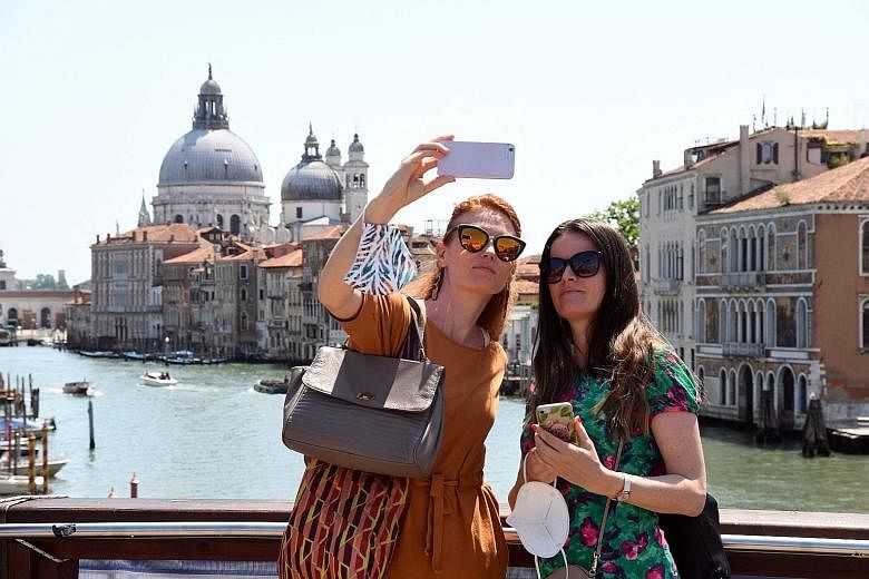 Tourists on a bridge over the Grand Canal in Venice last month. A European Union Covid-19 travel certificate launched yesterday may help some make trips, but arrivals to tourist hot spots from Portugal to Croatia are set to remain well down from norm