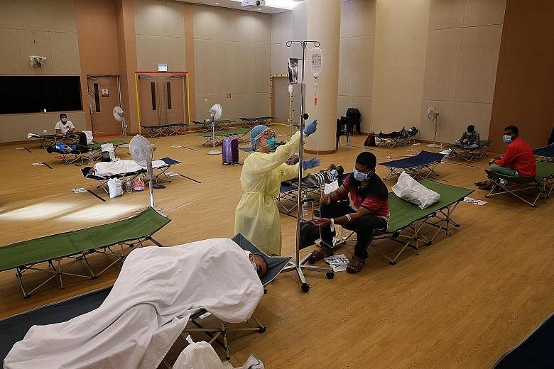 A nurse attending to a migrant worker on drip at Jurong Community Hospital in April last year. The Government has announced salary hikes of 5 per cent to 14 per cent for nurses from this month. ST FILE PHOTO