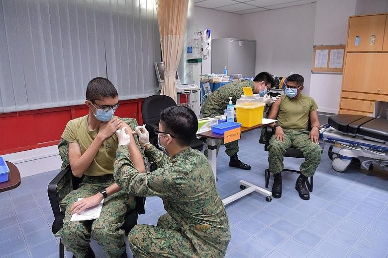 Above: A Singapore Armed Forces combat medic receiving a Pfizer-BioNTech Covid-19 jab in January. BioNTech is among Temasek's portfolio firms. PHOTO: MINDEF/FACEBOOK Left: People collecting free masks provided by Temasek during one of its nationwide 