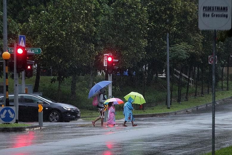 Pedestrians crossing the road in the rain at Sumang Lane in Punggol on Tuesday. On that day and on Monday, Singapore saw prolonged and widespread showers, with the mercury dipping to 22.5 deg C in Admiralty on Tuesday morning.
