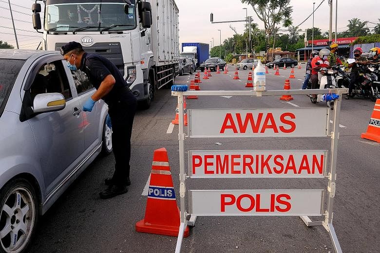 A police officer checking motorists' documentation at a checkpoint in Kuala Langat, Selangor, yesterday. The state remains the epicentre of infections, with cumulative cases standing at 307,094. PHOTO: BLOOMBERG Mr Mohd Akil Maalim, 87, being vaccina