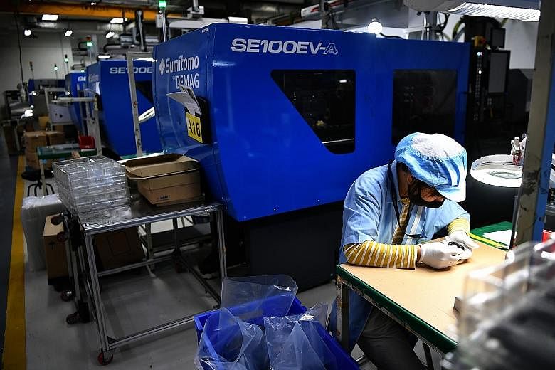 A worker at plastics manufacturer Sanwa Plastic examining a product in the production area. Manufacturing is one of the sectors that are not likely to see much impact from tightened Covid-19 measures. ST PHOTO: LIM YAOHUI