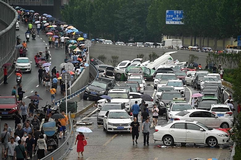 Cars sitting in flood waters following heavy rain in Zhengzhou in China's central Henan province yesterday. The rainy season has hit the country hard, with Henan province recording the highest rainfall to date. Over 200mm of rain fell in one hour in 