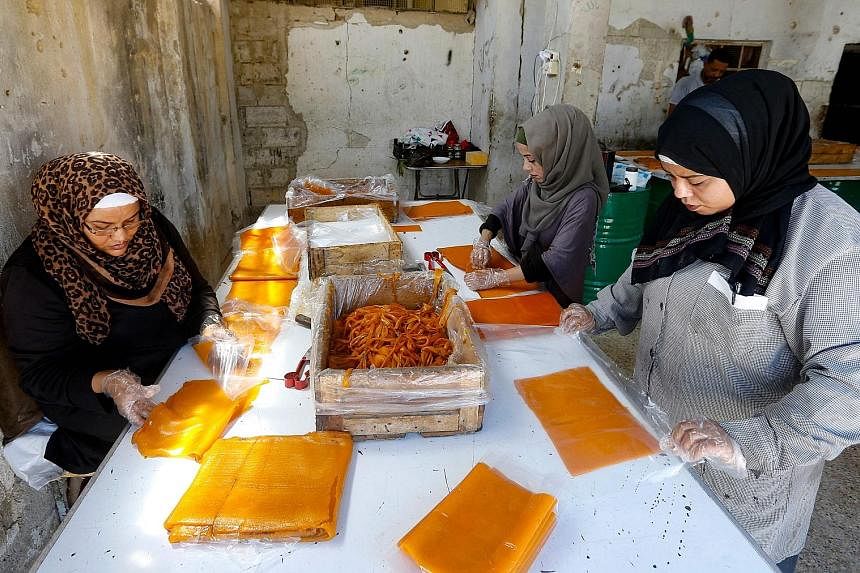 Apricot juice is mixed with sugar, then cooked and spread onto wooden boards (right) to be left to dry in the sun (above) in the Eastern Ghouta region on the outskirts of the Syrian capital Damascus. It is part of the process to make the popular Qama