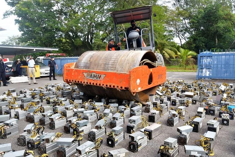 Police at the Miri district police headquarters using a steamroller to crush Bitcoin-mining machines. The authorities in Sarawak discovered the machines in crackdowns between February and April.