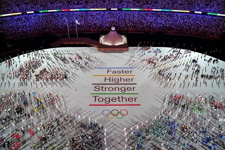 Above: Athletes gathering around the new motto last night in the stadium. Left: One of the performances during the ceremony.