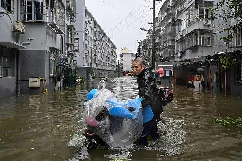 A man pushing a scooter in a flooded street in Ningbo, Zhejiang province, yesterday as Typhoon In-fa lashed the eastern coast of China.