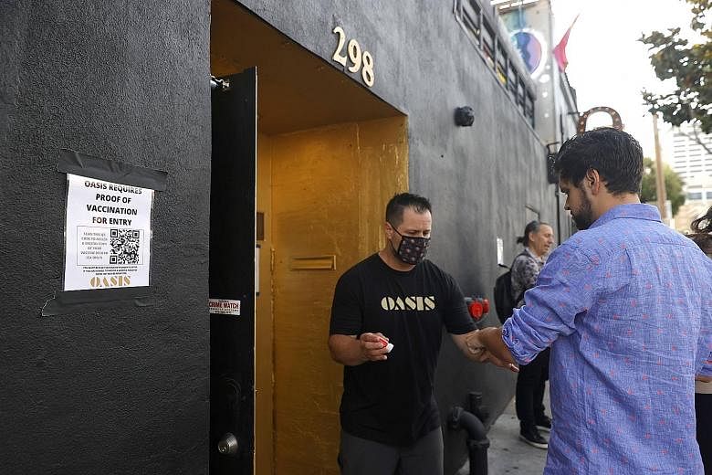 A doorman checking a customer's vaccination card before allowing him to enter a bar in San Francisco on Thursday. As at Monday, the four-week Covid-19 case count in the United States more than doubled from the previous four weeks. Cases and hospitali