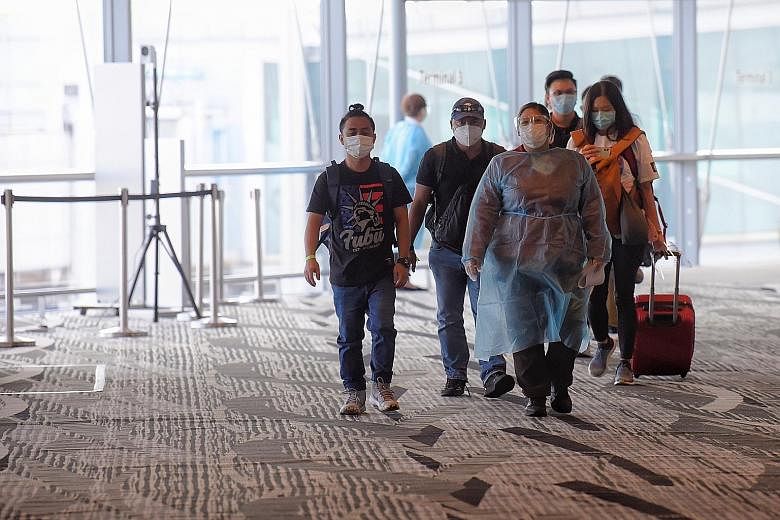 A Changi Airport staff member (in personal protective equipment) escorting arriving passengers in May. There were 48,724 short-term visit pass holders in Singapore as at end-June. ST PHOTO: MARK CHEONG