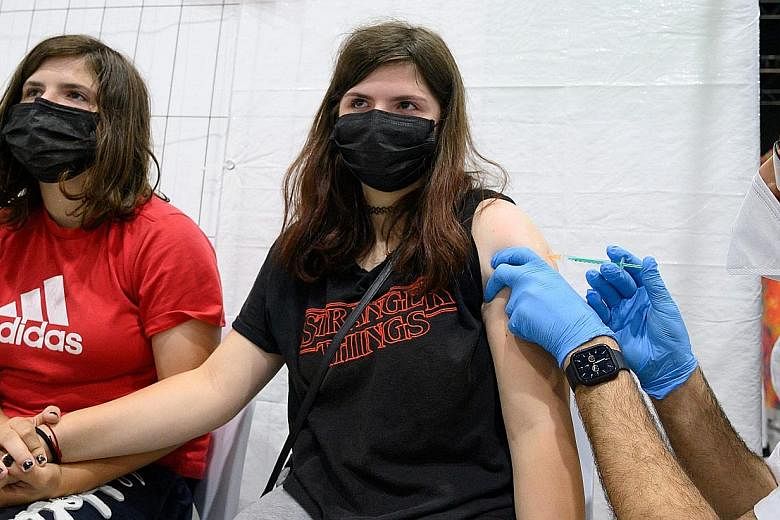 Nicole (left) holding the hand of her 12-year-old twin sister Jessica as she got her Pfizer-BioNTech jab in Ludwigsburg, southern Germany, yesterday. Germany is encouraging vaccination among teens by opening all the country's vaccination centres to t
