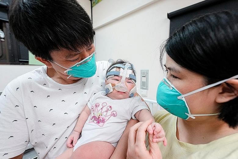 Left: When she was born in June last year, Kwek Yu Xuan weighed 212g. Below: Yu Xuan, with mum Wong Mei Ling and dad Kwek Wee Liang, both 35. She weighed 6.3kg when she was discharged last month. PHOTOS: NUH, COURTESY OF KWEK FAMILY