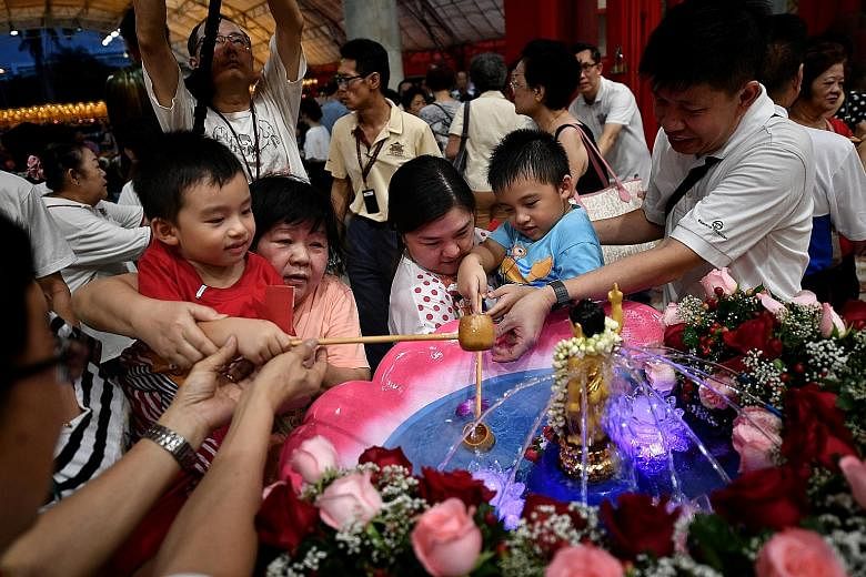 Devotees performing the bathing of Prince Siddhartha rite, in which a statue of Buddha as a baby is bathed in perfumed water, symbolising the purification of unwholesome deeds at the Kong Meng San Phor Kark See Monastery in 2017. Practices on Vesak D