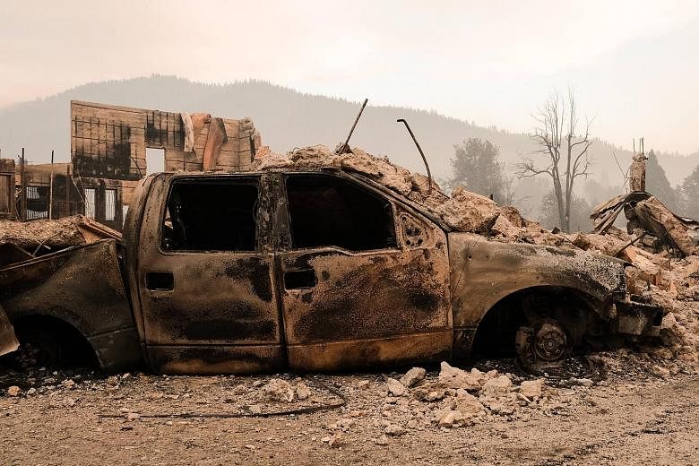 A charred vehicle destroyed by the Dixie Fire in front of the remains of a structure situated near Highway 89 in Greenville, California, on Sunday.