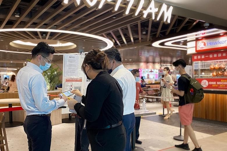 Patrons having their vaccination status checked on their TraceTogether mobile app by foodcourt staff at Plaza Singapura on Tuesday. Only fully vaccinated individuals will receive a yellow sticker and are allowed to dine in, while those non-fully vacc
