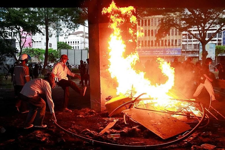 Demonstrators burning items during a protest in Bangkok yesterday over the Thai government's handling of the coronavirus outbreak. PHOTO: REUTERS