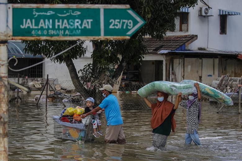 <p>epa09652236 A man (L) pushes a trolley cart with his son and belongings, as others family members carry a mattress, after floods struck Taman Sri Muda, Shah Alam district, some 40km from Kuala Lumpur, Malaysia, 21 December 2021. Flooding in Malaysia le