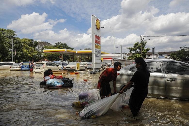 Victims pulls their belongings after floods struck Taman Sri Muda in Shah Alam on Dec 21, 2021.