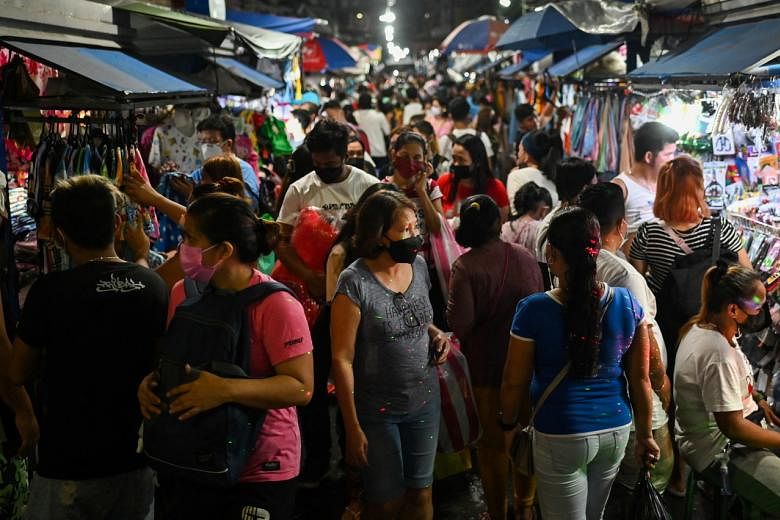 <p>People wearing face masks as protection against the coronavirus disease (COVID-19) walk past stores at a market in Manila, Philippines, December 18, 2021. REUTERS/Lisa Marie David</p>