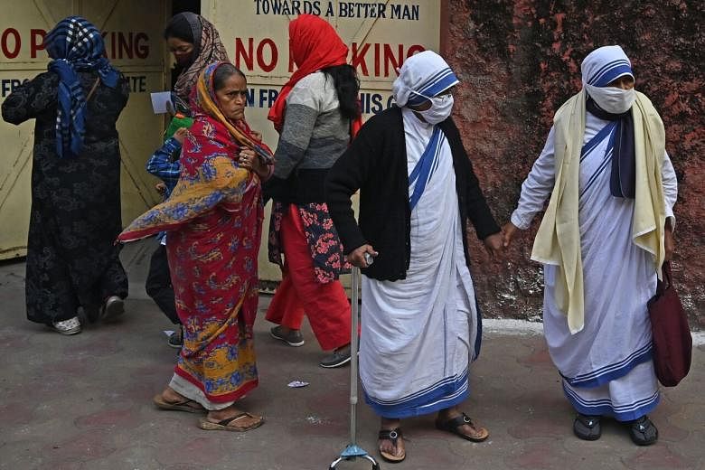 <p>Nuns from the Catholic Order of the Missionaries of Charity along with others walk after casting their vote at a polling station during the municipal corporation election in Kolkata on December 19, 2021. (Photo by Dibyangshu SARKAR / AFP)</p>