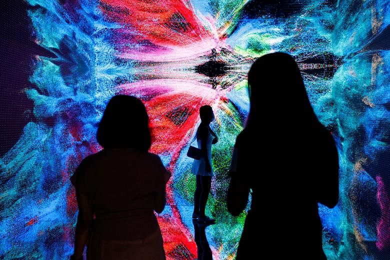 <p>FILE PHOTO: Visitors are pictured in front of an immersive art installation titled "Machine Hallucinations - Space: Metaverse" by media artist Refik Anadol, which will be converted into NFT and auctioned online at Sotheby's, at the Digital Art Fair, in