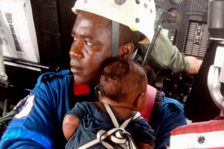 A Red Cross member carrying Yudier Moreno after he and his mother Nelly Murillo were rescued in Quibdo, Colombia, yesterday.