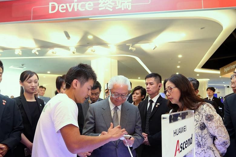 President Tony Tan, with Huawei chairman Sun Yafang (right), at the Huawei Executive Briefing Centre yesterday in Beijing, where he was introduced to Huawei's cellphone devices by a group of Singaporean university students, including Mr Chong Soon Se
