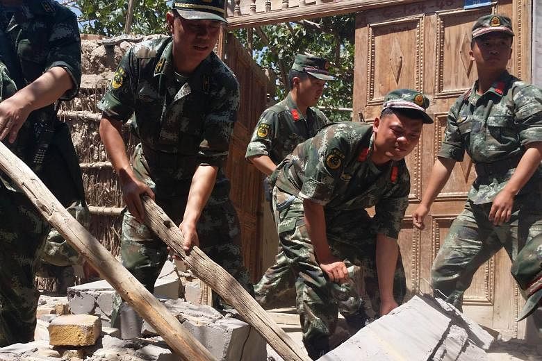 Soldiers helping villagers to dismantle damaged walls after the 6.4-magnitude quake struck Pishan county yesterday. A series of aftershocks followed, the strongest measuring 4.8.