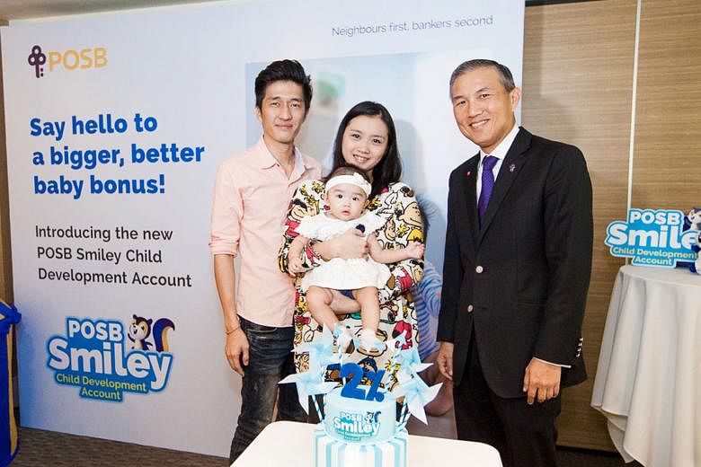 Mr Keith Tham (far left), with his wife, Ms Daphne Lian, their daughter Chloe, and Mr Jeremy Soo (left), managing director of DBS' consumer banking group, says he will switch his daughter's Child Development Account to POSB.