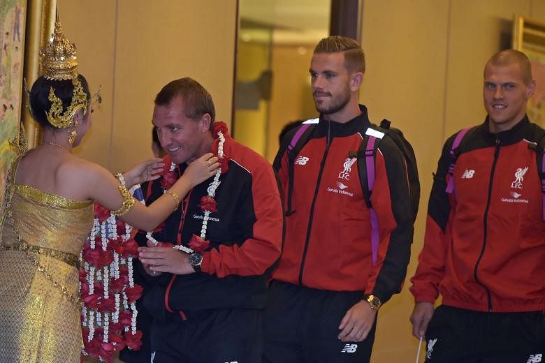 Liverpool manager Brendan Rodgers being garlanded upon arrival at Suvarnabhumi International Airport as Jordan Henderson and Martin Skrtel await their turn.