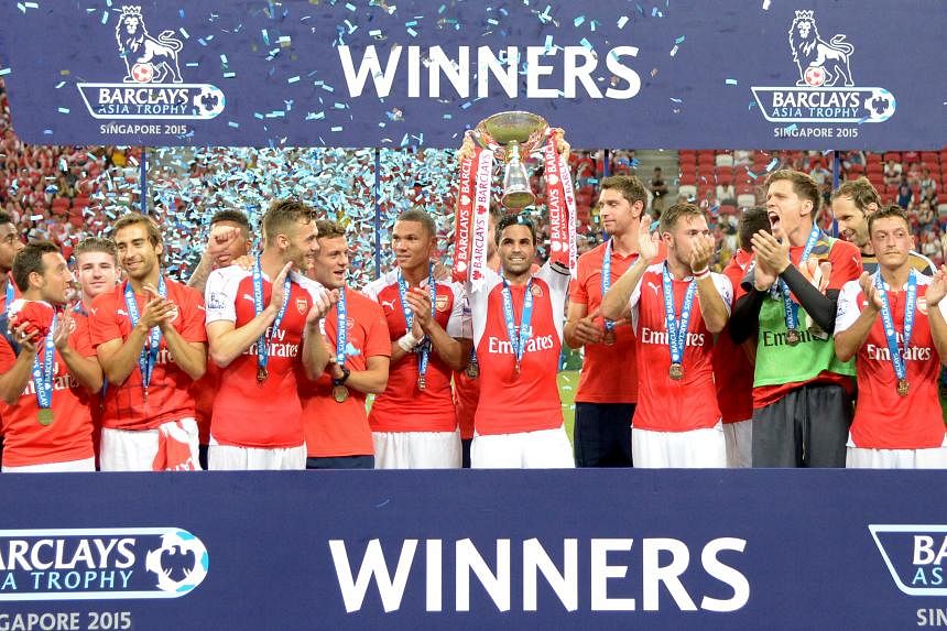 Arsenal club skipper Mikel Arteta lifting the Barclays Asia Trophy as his team-mates celebrate. Everton goalkeeper Joel Robles and right-back Seamus Coleman watching helplessly as Theo Walcott's shot crosses the line to give Arsenal a 1-0 lead.