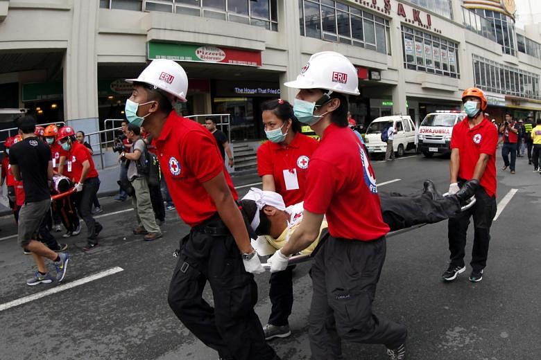 A Filipino rescuer (left) conducting a high-angle rescue operation during an earthquake preparedness drill yesterday at a building in Makati City, south of the Philippines' capital Manila. Thousands of people took part in the drill (above) to prepare