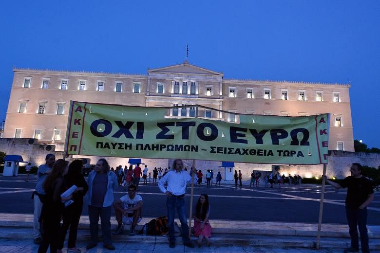 Demonstrators displaying a banner saying "No to Euro" in front of the Greek Parliament as lawmakers inside prepared to vote on a bailout package for the country. The deal will help Greece avoid a default next week when a payment to the European Centr