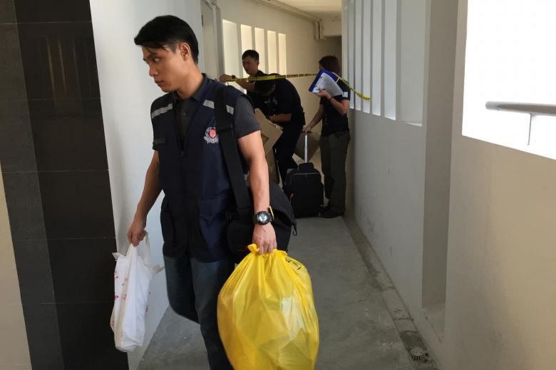 Police officers leaving the couple's Senja Road flat yesterday morning. The couple have been married for close to two years and have a 14-month-old daughter. Police have classified the case as murder.