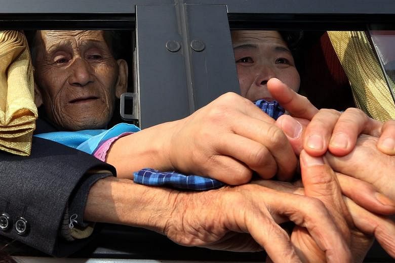 A file photo of separated families living in South Korea clasping the hands of their North Korean relatives inside a bus after a brief reunion. Such reunions are hugely emotional affairs for the largely elderly participants.