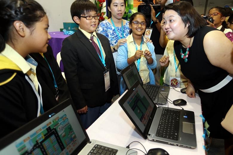 Ms Tan Swee Leng (right) of the People's Association, chatting with pupils yesterday at the Singapore Science Centre, where the children from Primary 4 to 6 showed the digital games they produced using a simple coding tool called Scratch to create ga