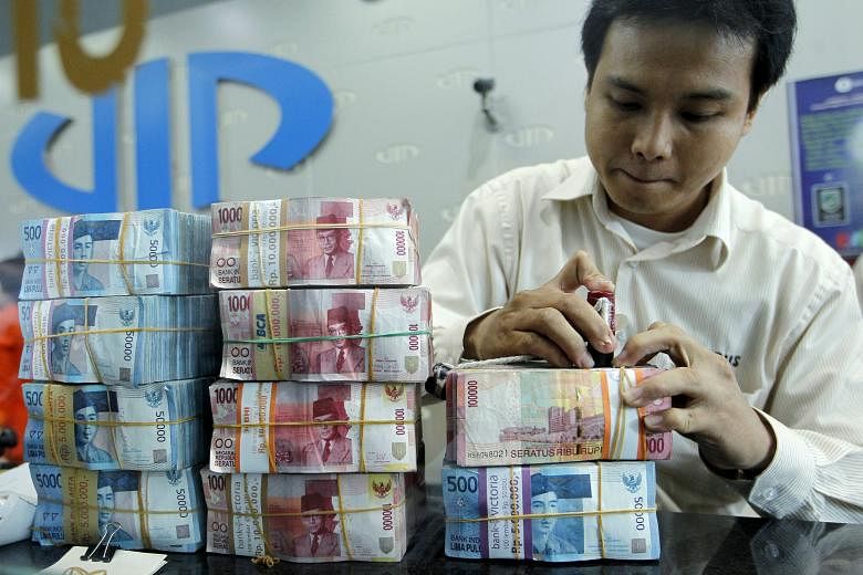 Rupiah notes being prepared for customers at a money changer in Jakarta. The Indonesian currency, like the ringgit, has tumbled to the lowest levels seen in 17 years. Yesterday, it traded at 10,334.3 against the Singdollar.