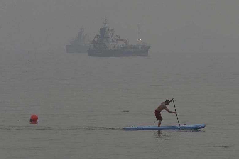 A man, undeterred by the air quality, on a paddle board at East Coast Park as the haze partly obscured ships in the distance at East Coast Park yesterday at around 6pm. NEA forecast the 24-hour PSI to be in the high end of the unhealthy range and low